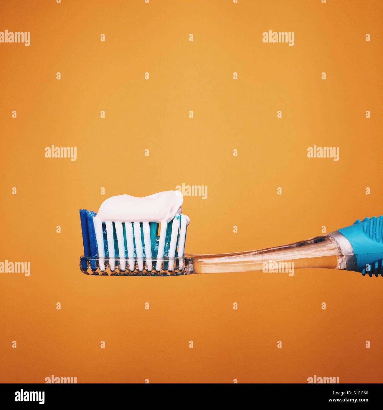 Single toothbrush with toothpaste against a yellow background Stock