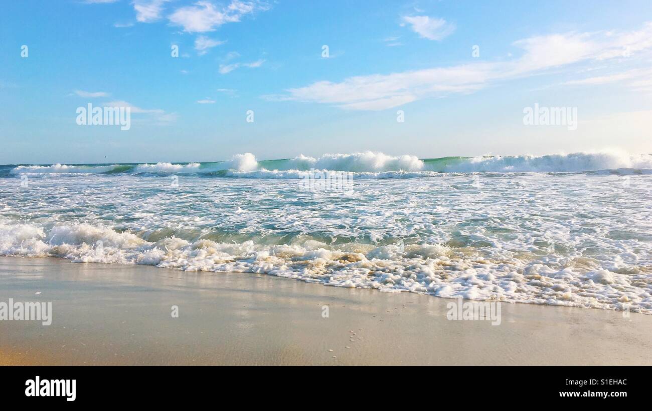 Seascape. Looking at the ocean from a sandy beach on a sunny day. Pastel colours. 16x9. Background. Space for copy. - Smartphone Captured Stock Image