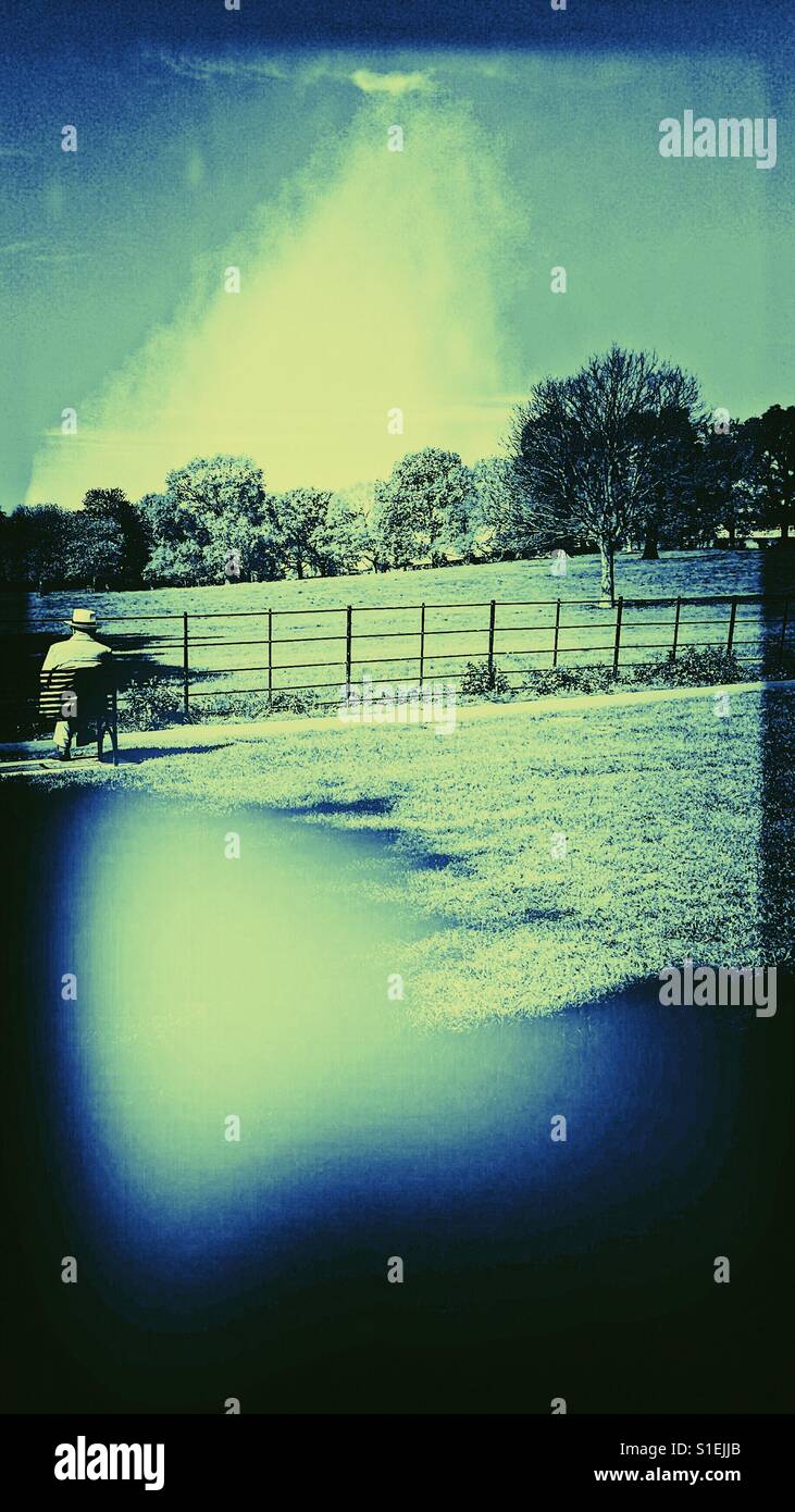 Man in hat sitting alone in park - Smartphone Captured Stock Image