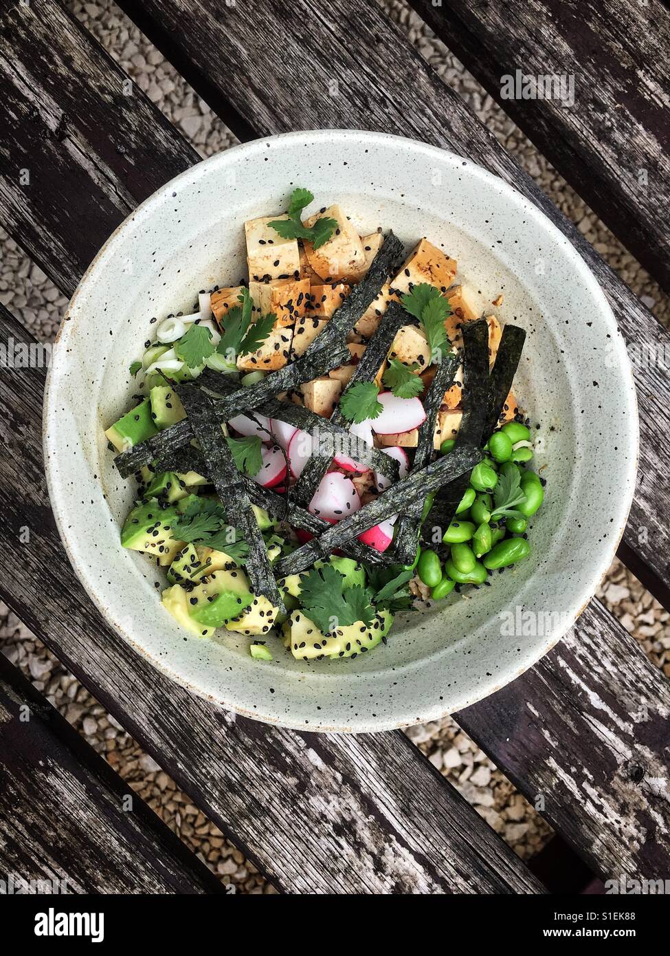 A white bowl of Hawaiian Poke with tofu, edamame beans, avocado, black