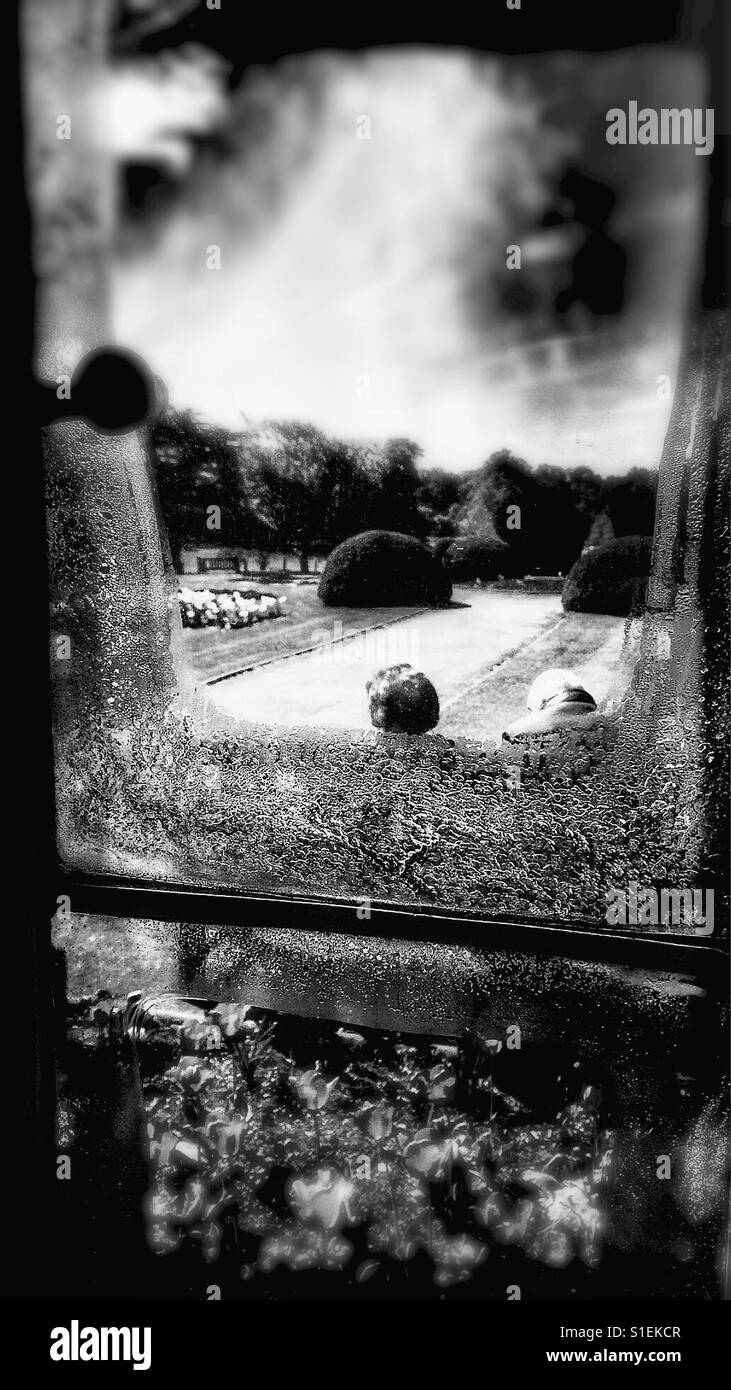 View through window of two people sitting on seat, England - Smartphone Captured Stock Image