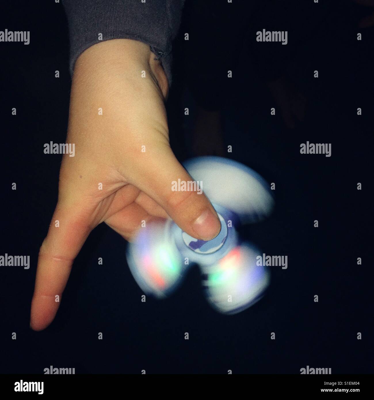 Boy playing with a light up fidget spinner - Smartphone Captured Stock Image
