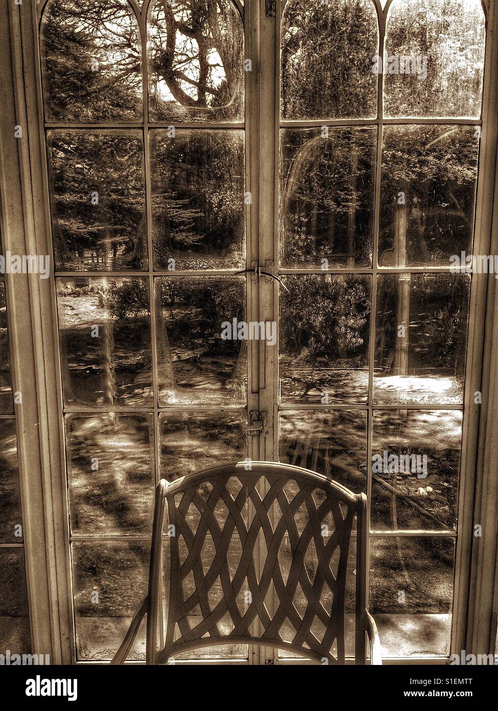 Vintage style image of chair by windows next to garden - Smartphone Captured Stock Image