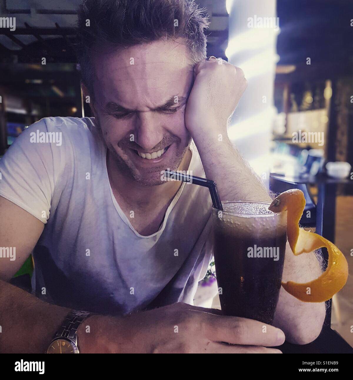 Man laughing whilst drinking a cocktail - Smartphone Captured Stock Image