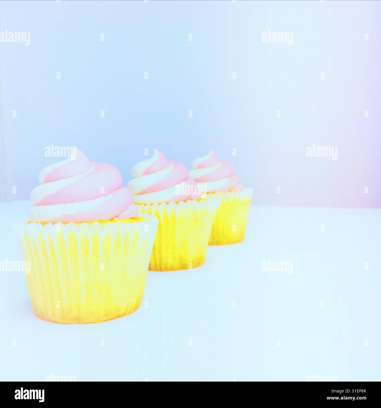 Three vanilla strawberry cupcakes on a light background. Space for copy. - Smartphone Captured Stock Image