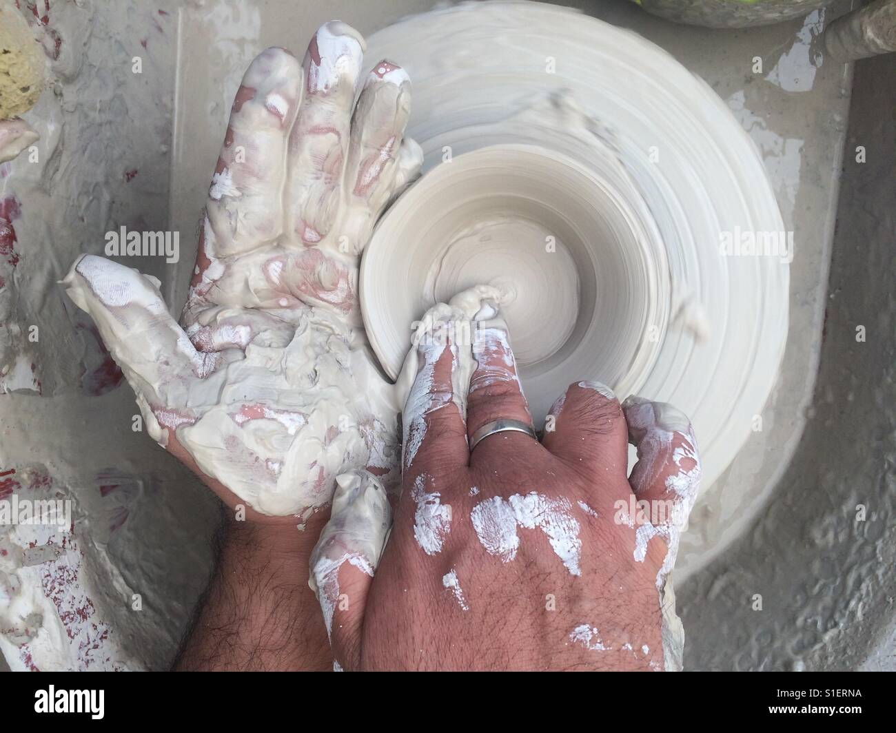 Hands on clay and potters wheel Stock Photo
