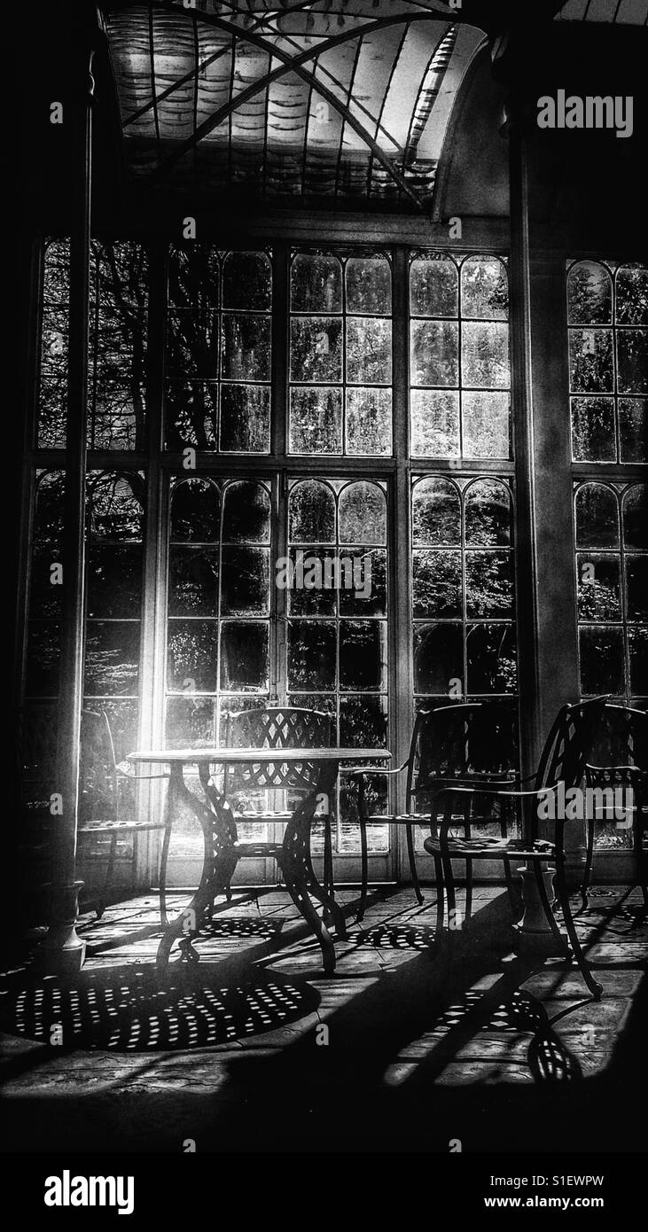 Table and chairs in sunlight in glasshouse - Smartphone Captured Stock Image