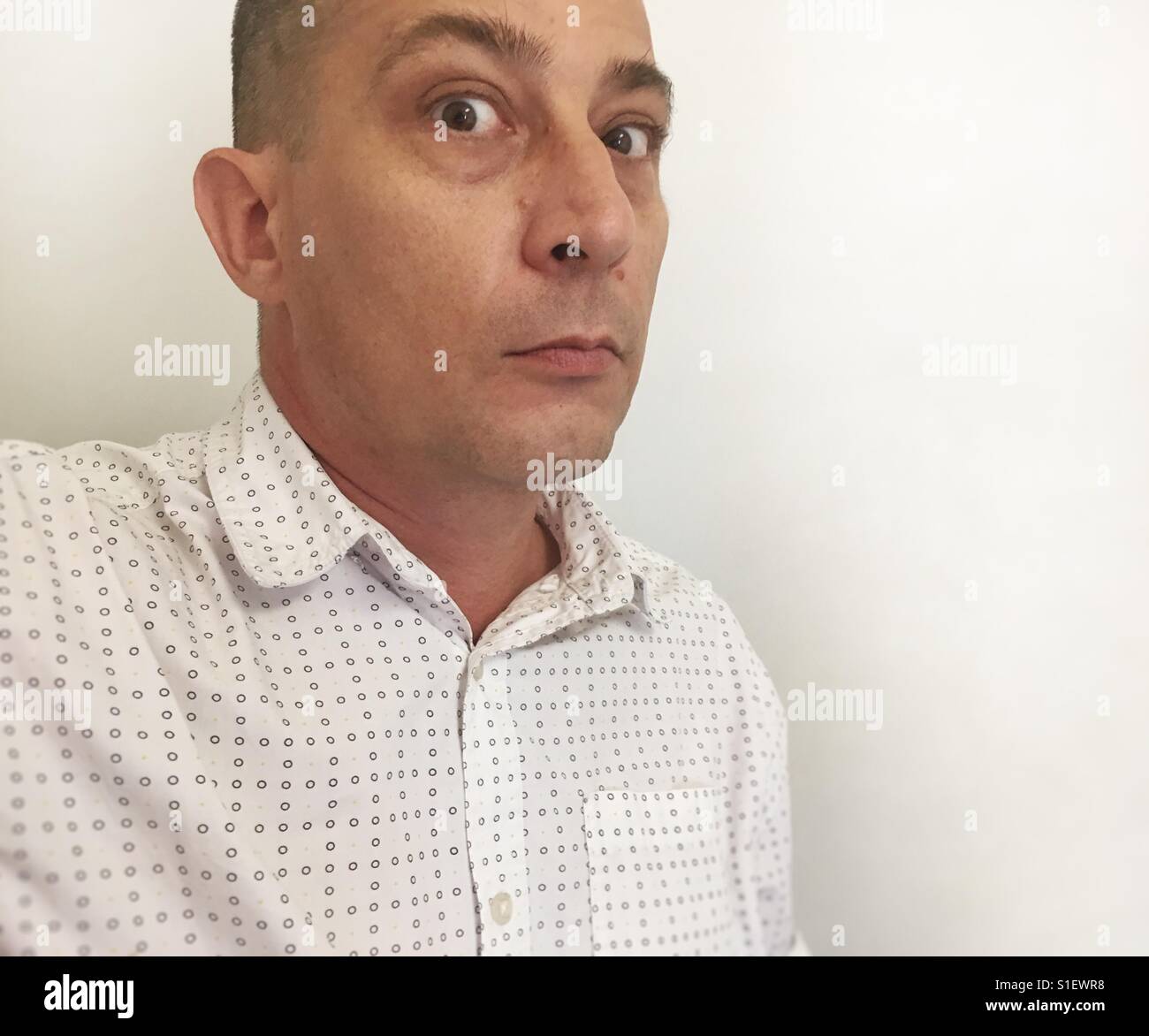 Surprised man against a white wall. - Smartphone Captured Stock Image