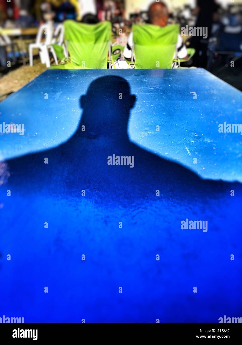 Shadow of a bald man on a blue table. - Smartphone Captured Stock Image