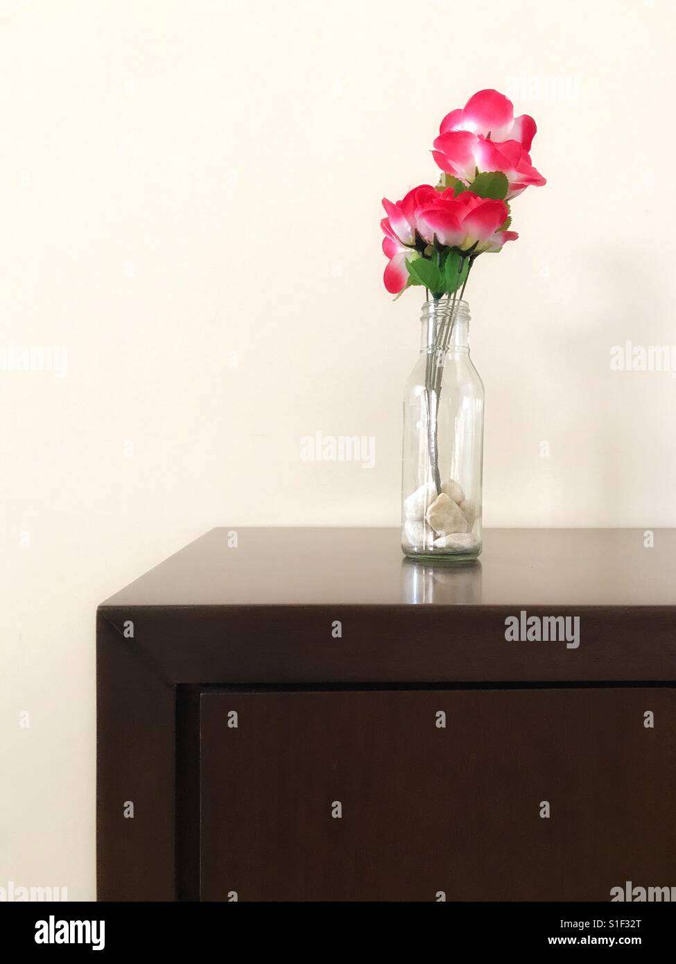 Flower on a wood rack against a off-white wall Stock Photo
