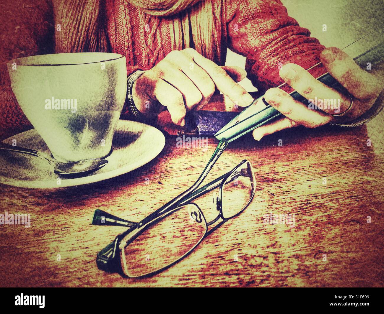 Woman using wireless technology seated at a table with a hot drink - Smartphone Captured Stock Image