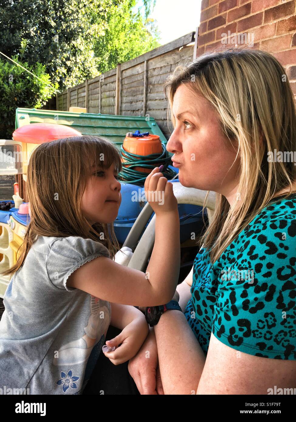 Little girl doing Mummies make up in the garden. Stock Photo