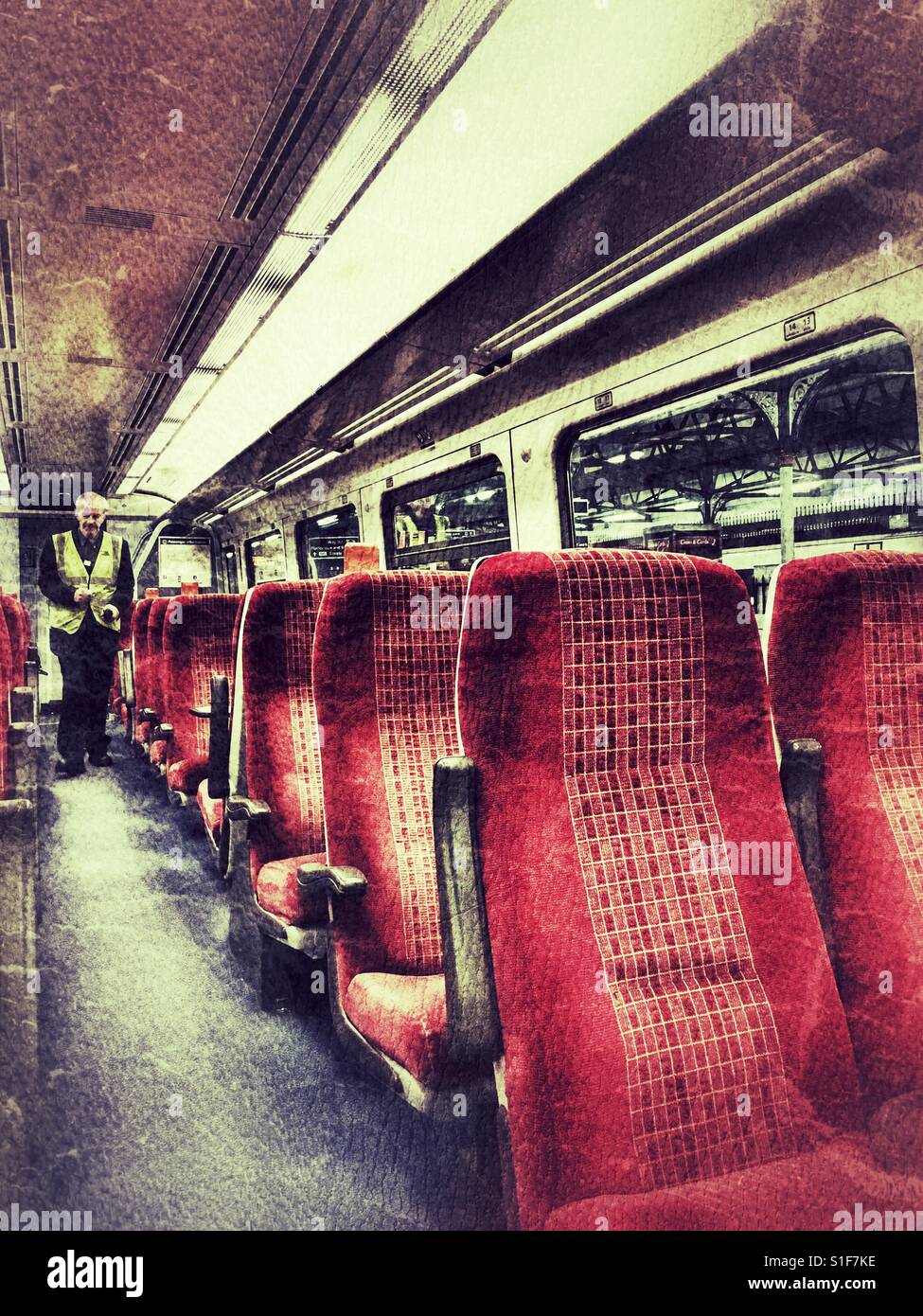 Man in high visibility yellow jacket walking down aisle of empty train carriage - Smartphone Captured Stock Image