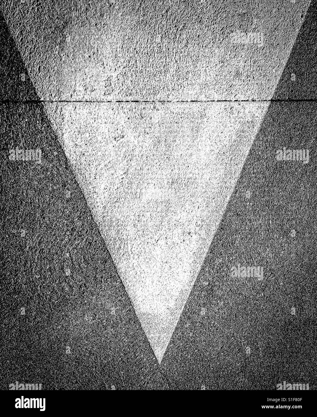 Downward facing painted triangle on pavement Stock Photo