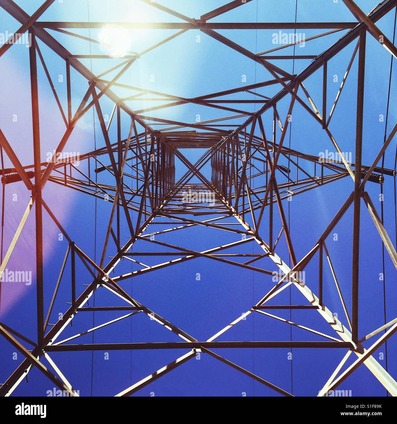 Looking up to a blue sky through an electrical tower Stock Photo - Alamy