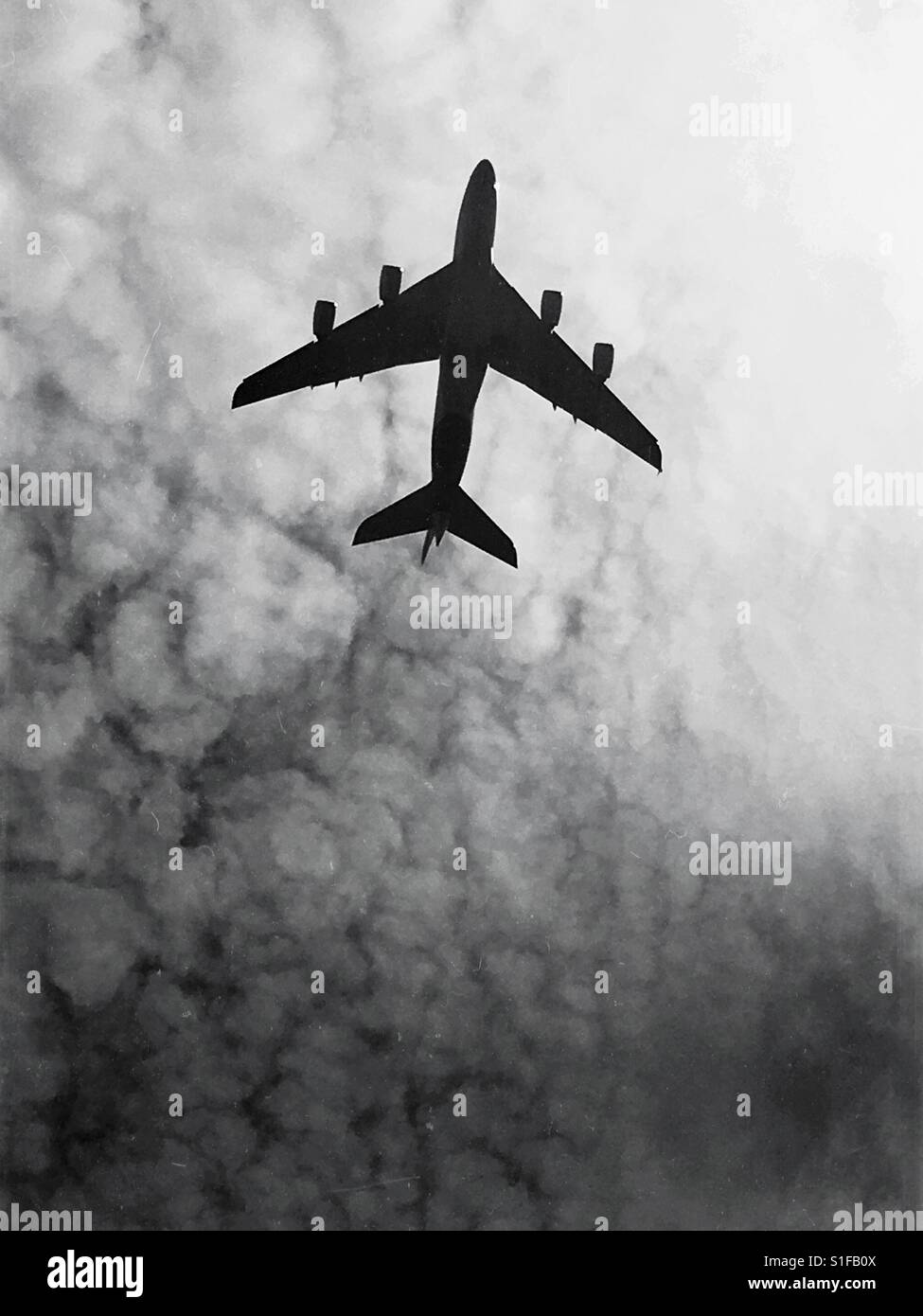 Silhouette of an aeroplane in flight against a cloudy grey sky Stock ...