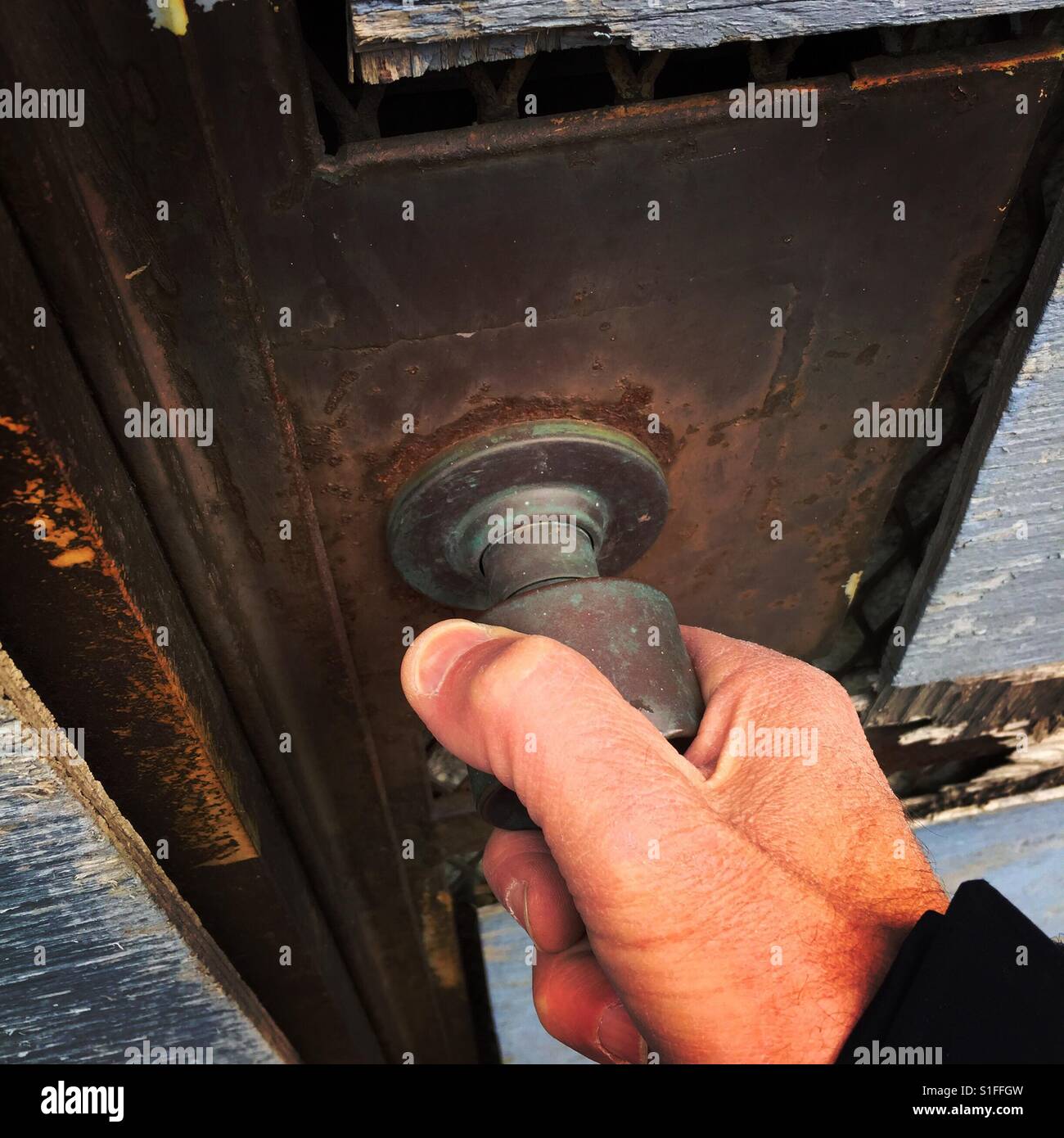 A man's hand grabs the door knob of a dilapidated door Stock Photo