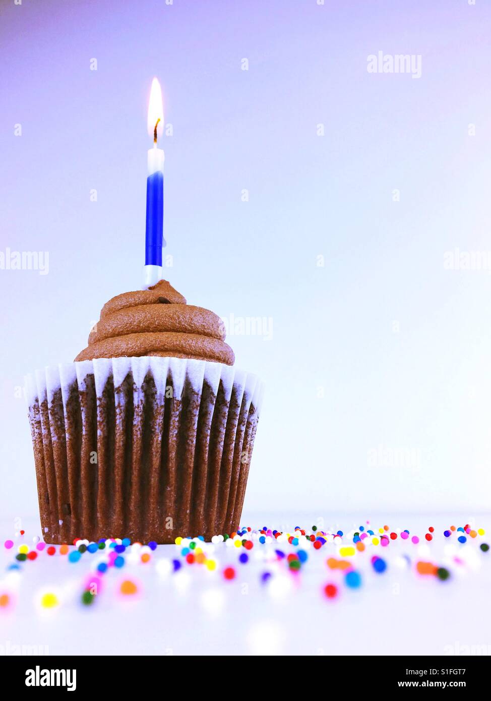 Chocolate cupcake with blue birthday candle. Room for copy. - Smartphone Captured Stock Image