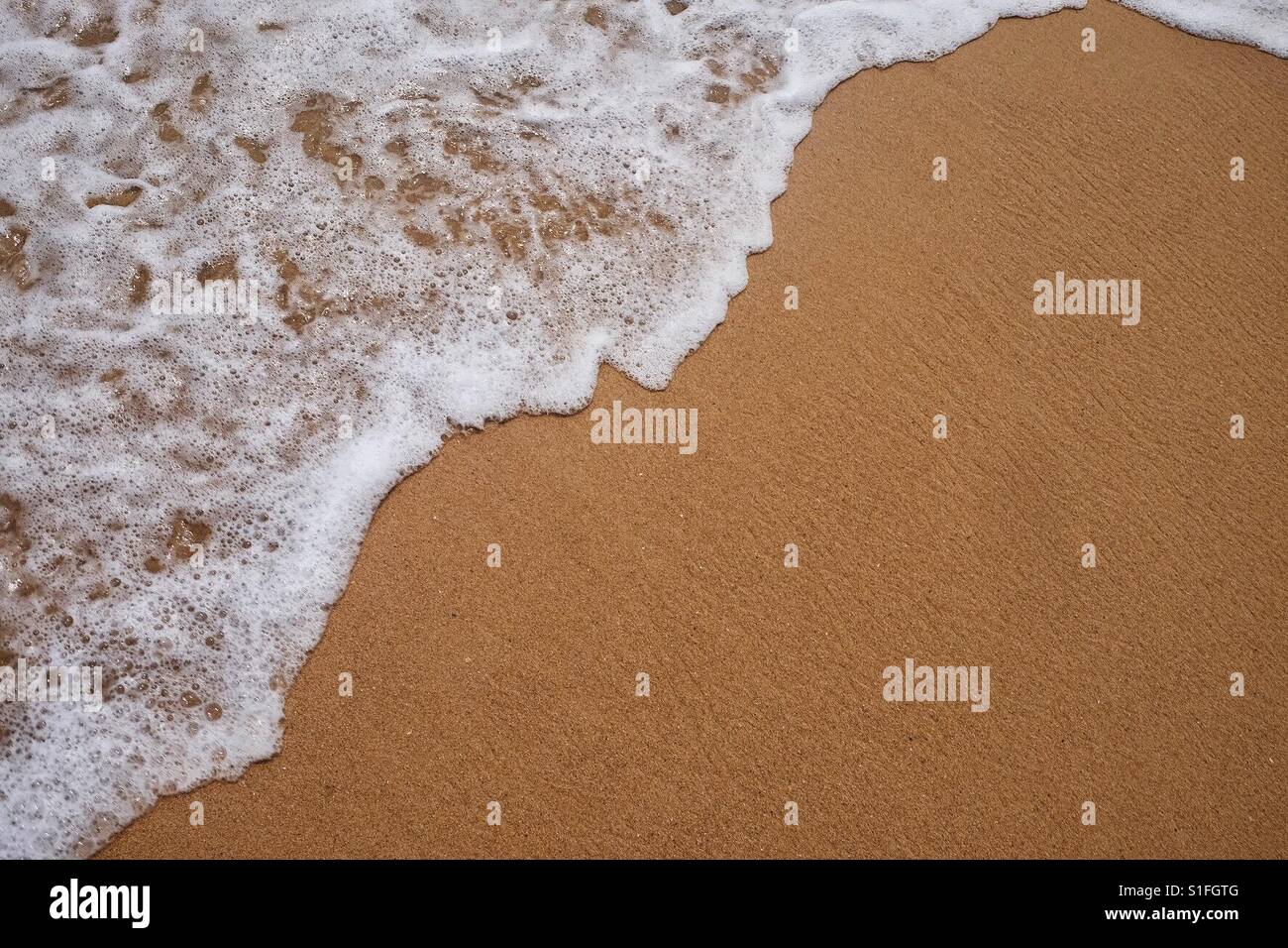 A sea foam wave on yellow sand. Background sea shore. Stock Photo