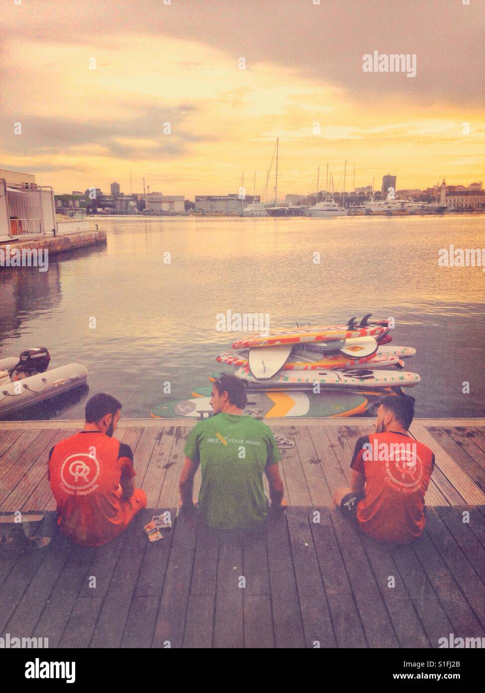 Friends sit and have a chat on the edge of a marina. - Smartphone Captured Stock Image