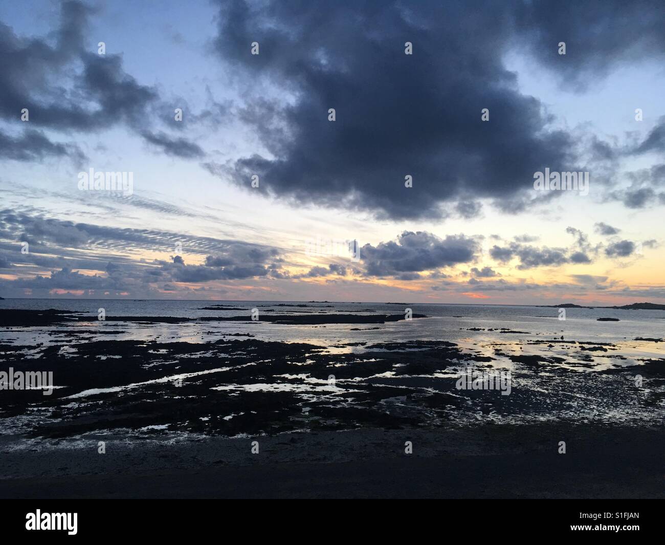 Sunset on a rocky beach on channel island of Guernsey in England - Smartphone Captured Stock Image