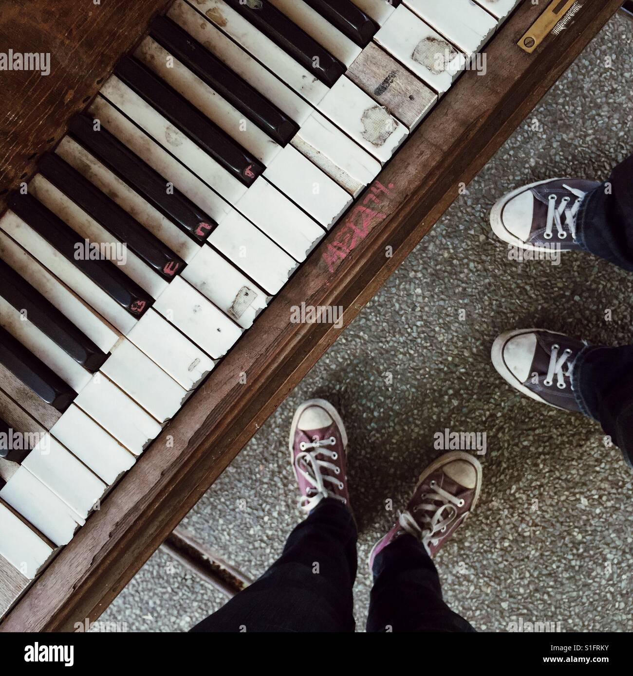 A male and female standing next to a dilapidated piano Stock Photo
