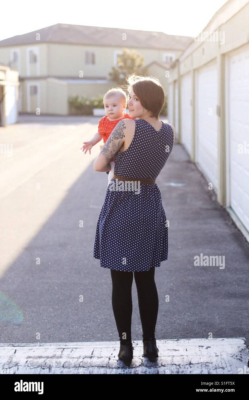 Hip Young Mom With Tattoos And Short Hair Holding Baby Daughter