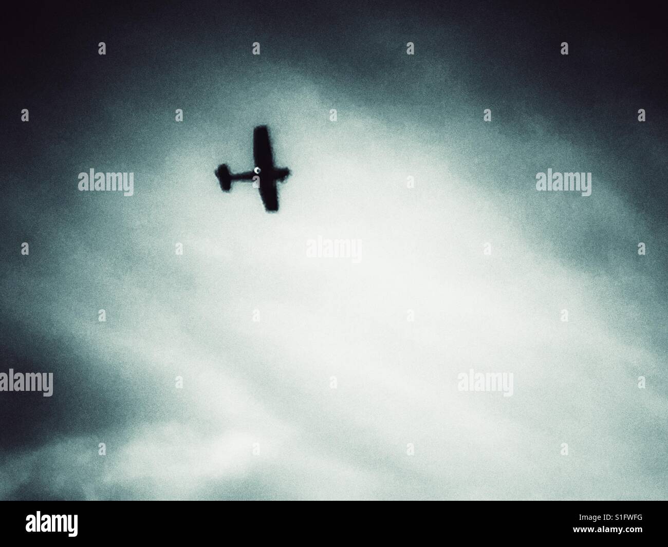 Light aircraft flying through dark clouds - Smartphone Captured Stock Image