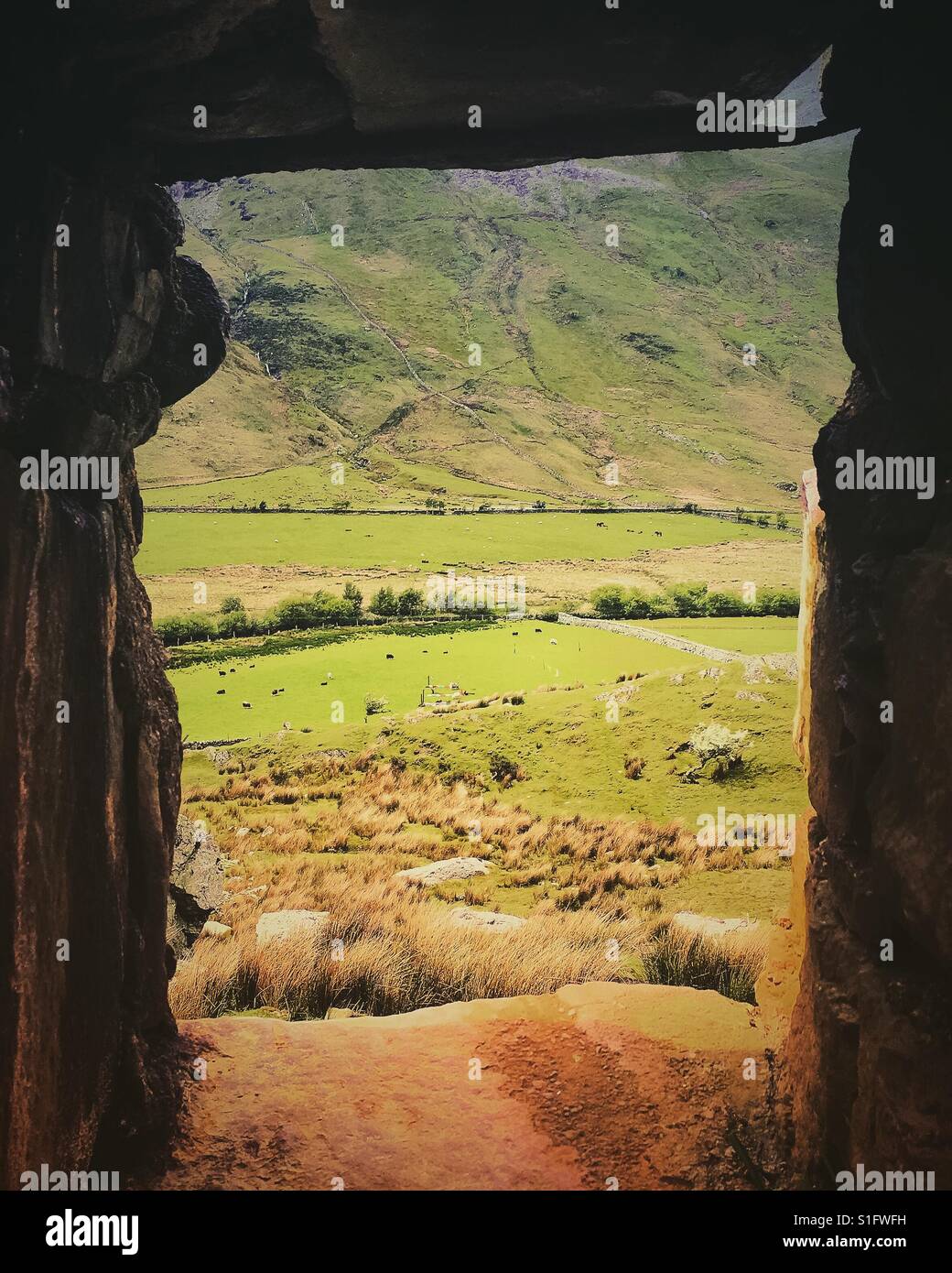 A photograph taken in Snowdonia National Park in Wales, looking through a gap in the stone wall at the landscape. - Smartphone Captured Stock Image
