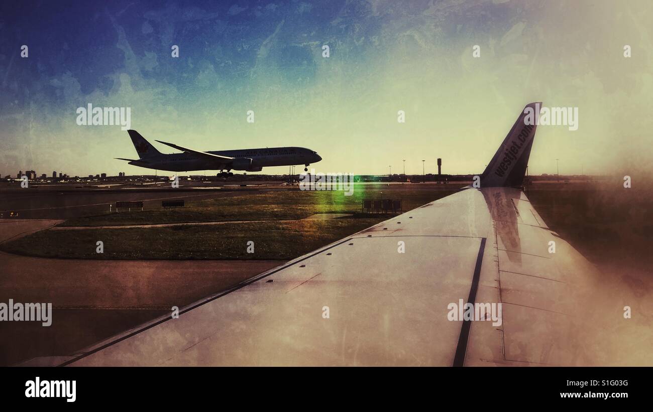 Looking out the window of an airplane at an other plane in the process of landing. - Smartphone Captured Stock Image