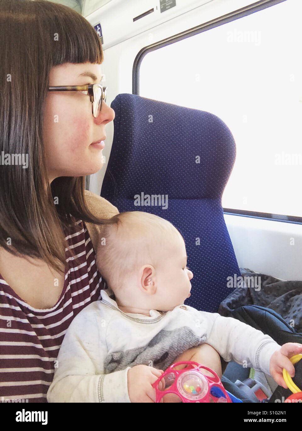 Mother holding baby son traveling on a train Stock Photo