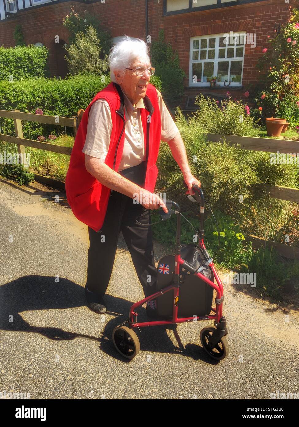 Elderly woman using a wheeled walking frame, Bawdsey, Suffolk, UK. - Smartphone Captured Stock Image