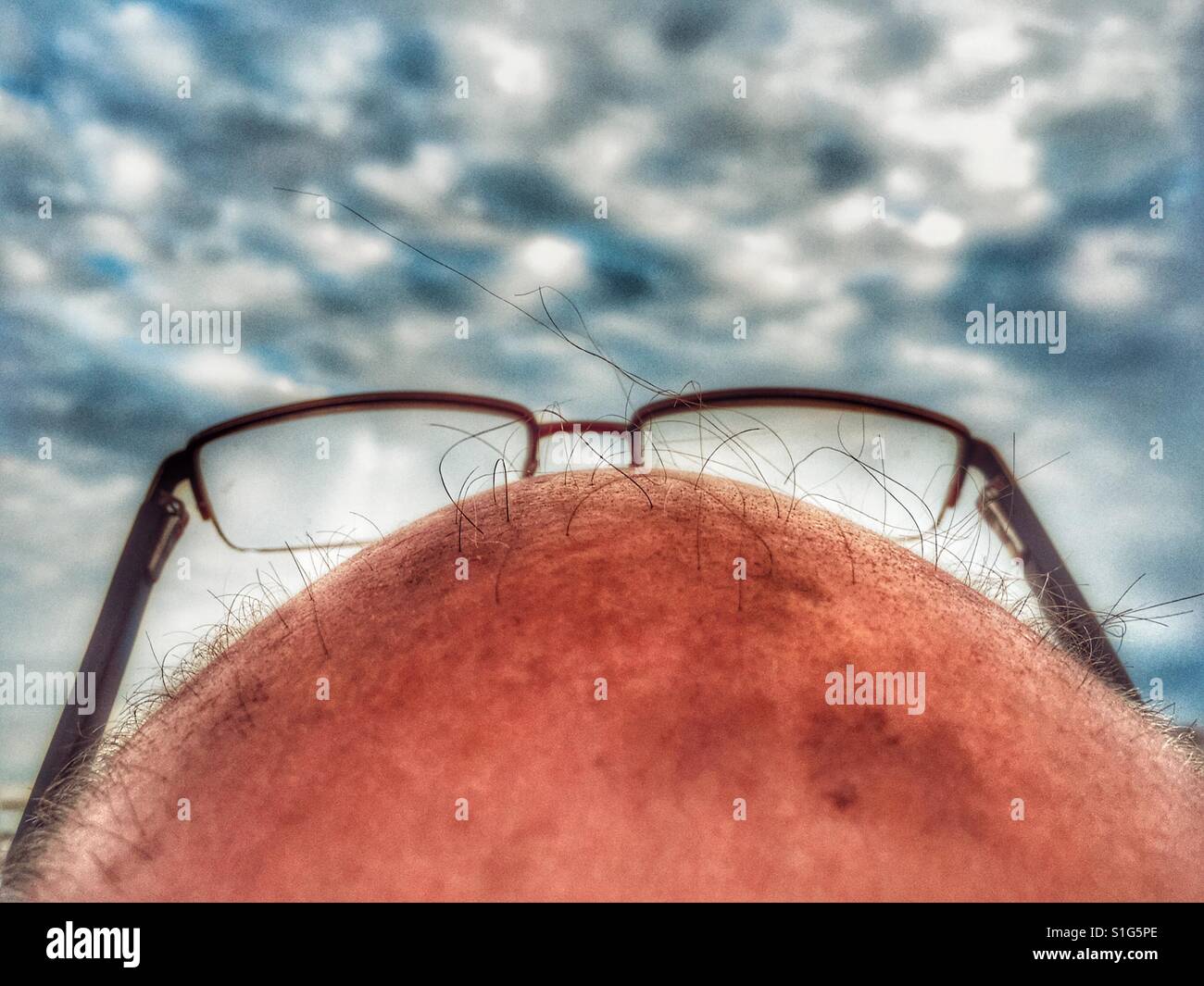 Bald headed man wearing reading glasses - Smartphone Captured Stock Image