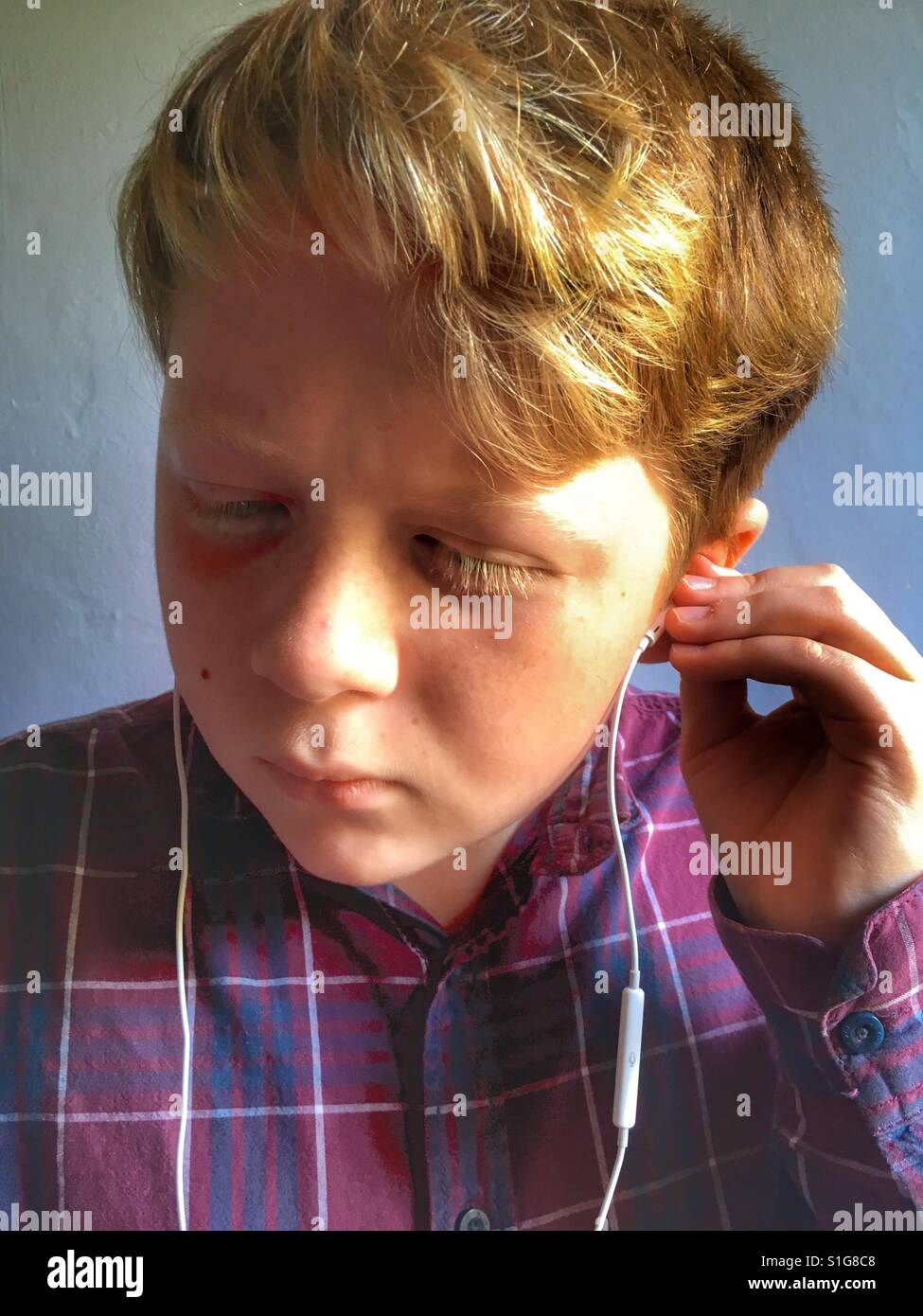 11-year old boy listening to music on iPhone - Smartphone Captured Stock Image