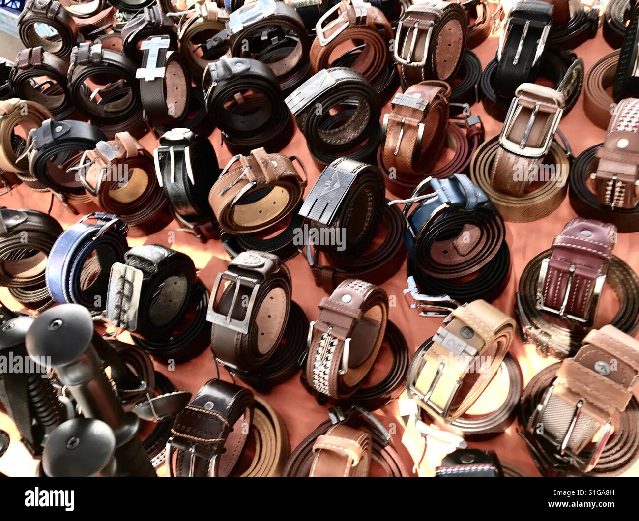 A selection of leather belts for sale on a Spanish market stall. - Smartphone Captured Stock Image