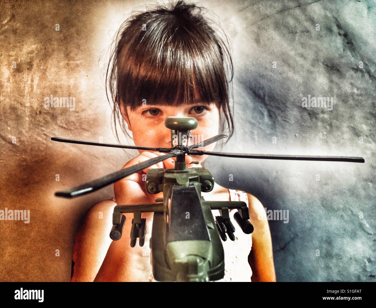 Girl playing with Apache toy helicopter - Smartphone Captured Stock Image