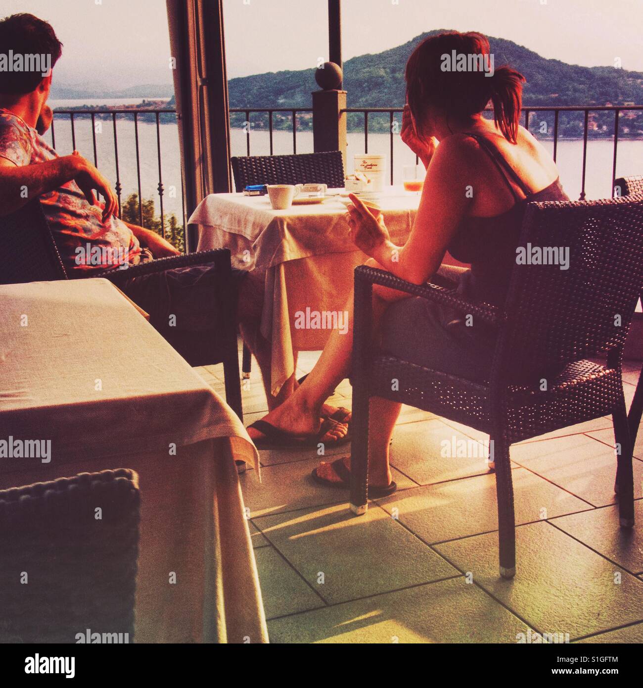 A couple enjoys a summer sunset on a terrace over a lake - Smartphone Captured Stock Image