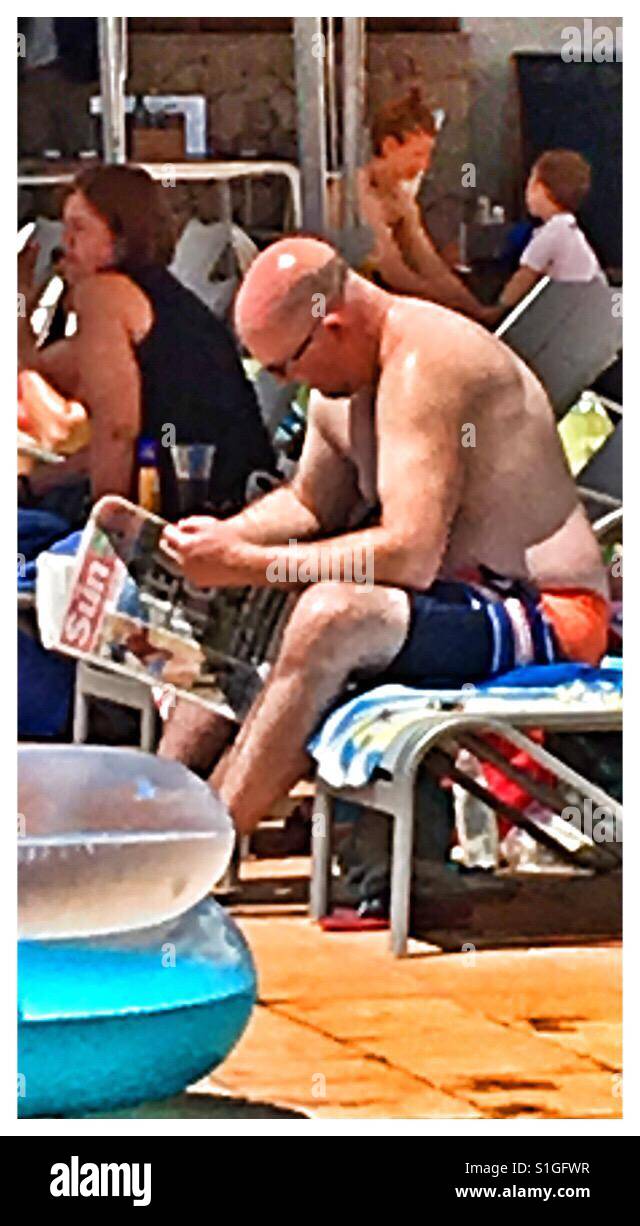 Tourist in Spain reading The Sun tabloid newspaper. Stock Photo