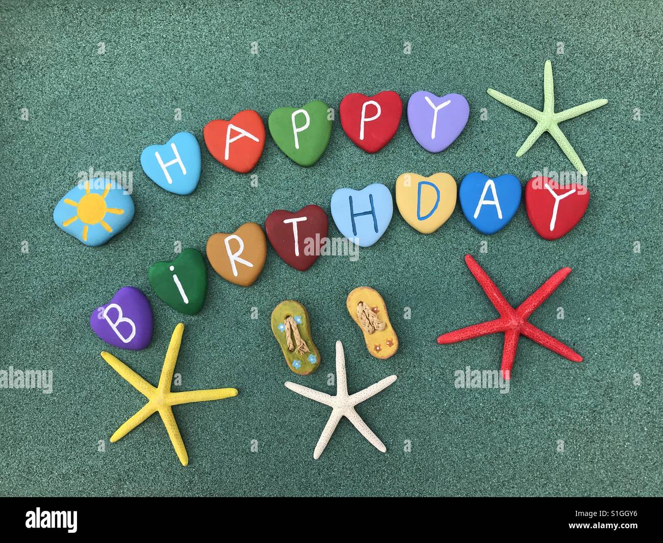 Happy Birthday With Multicolored Stone Hearts And Starfishes Over Green Sand Stock Photo Alamy