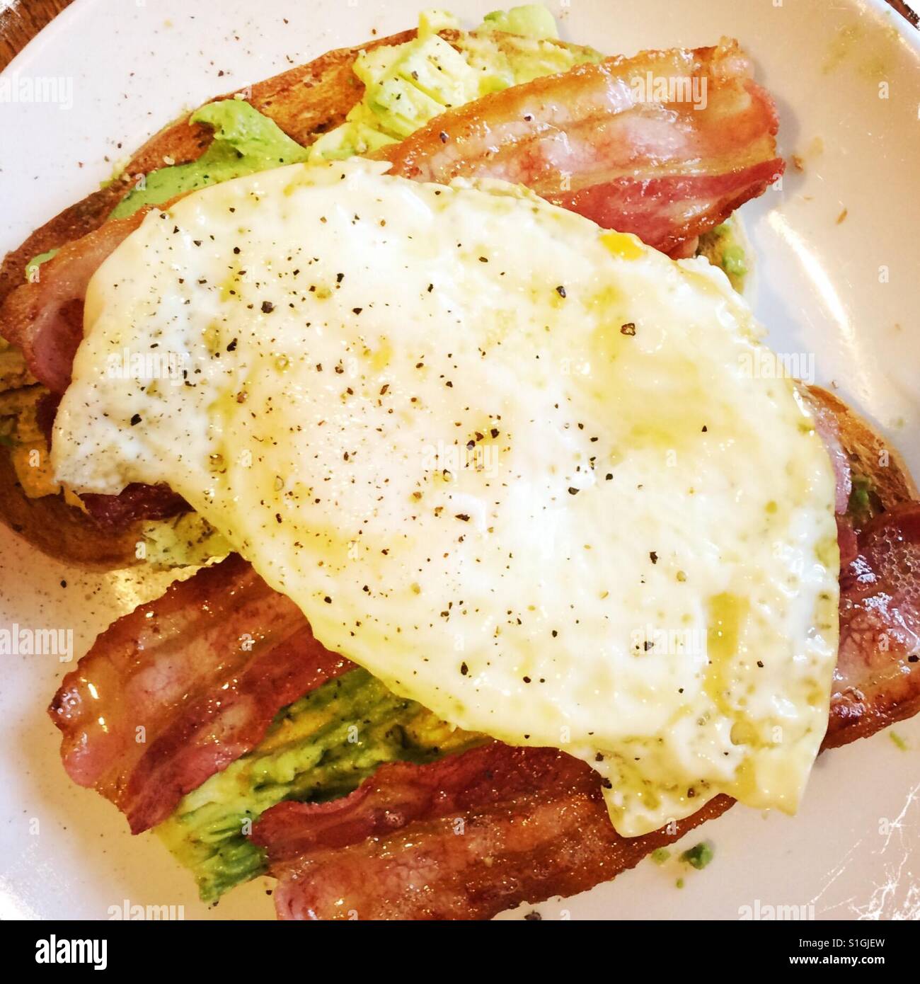 Mashed avocado on toast with fried egg and bacon on top. - Smartphone Captured Stock Image
