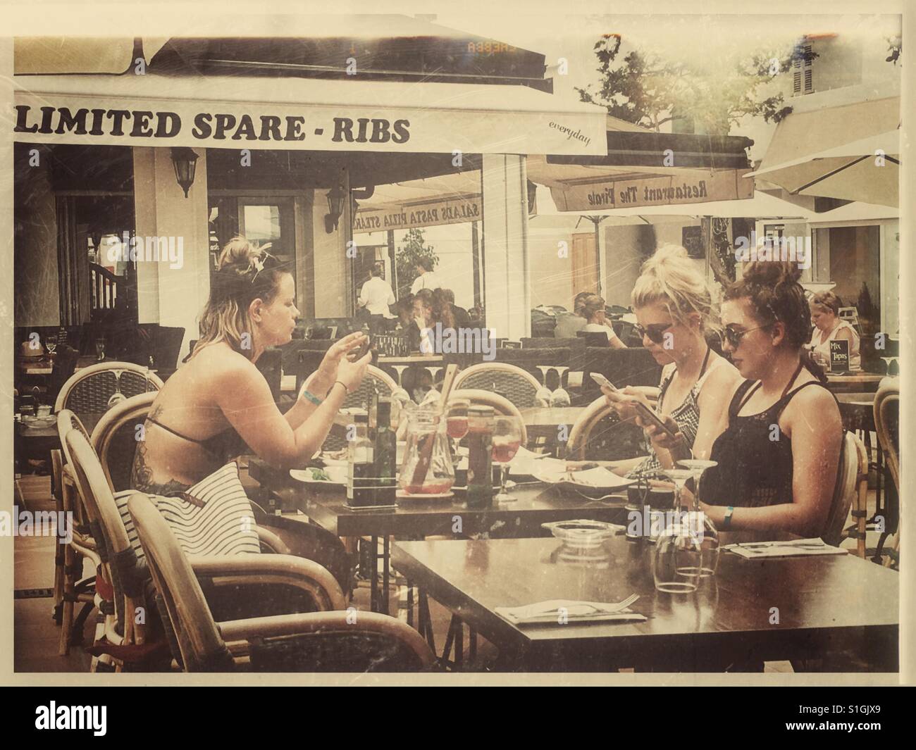 Three women on holiday all using their mobiles. Stock Photo