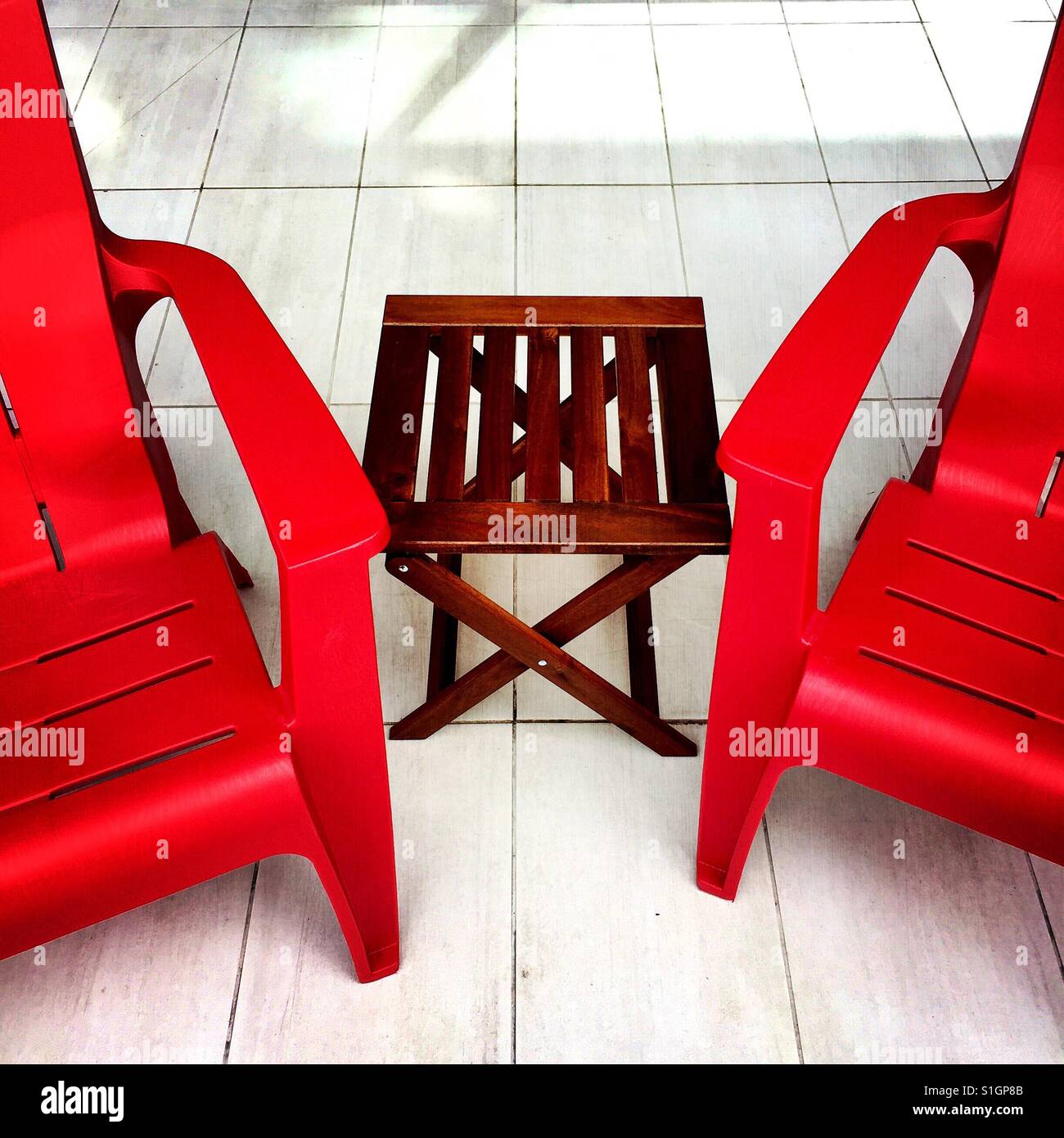 Empty red chairs and a wood table on an outdoor patio Stock Photo