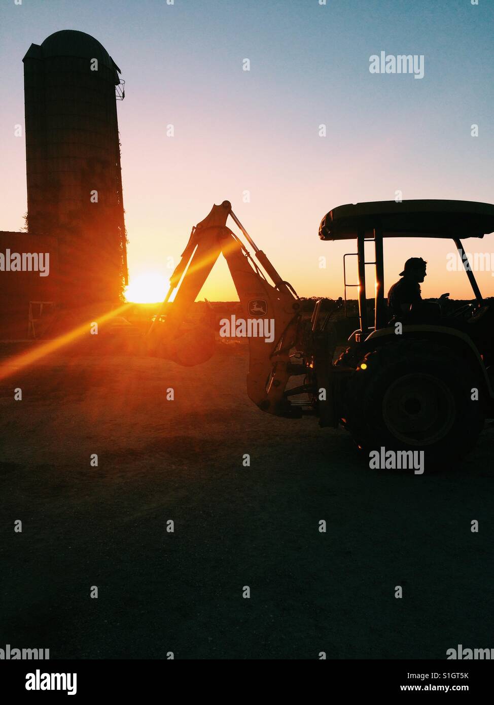 Silhouette of tractor against sunset - Smartphone Captured Stock Image