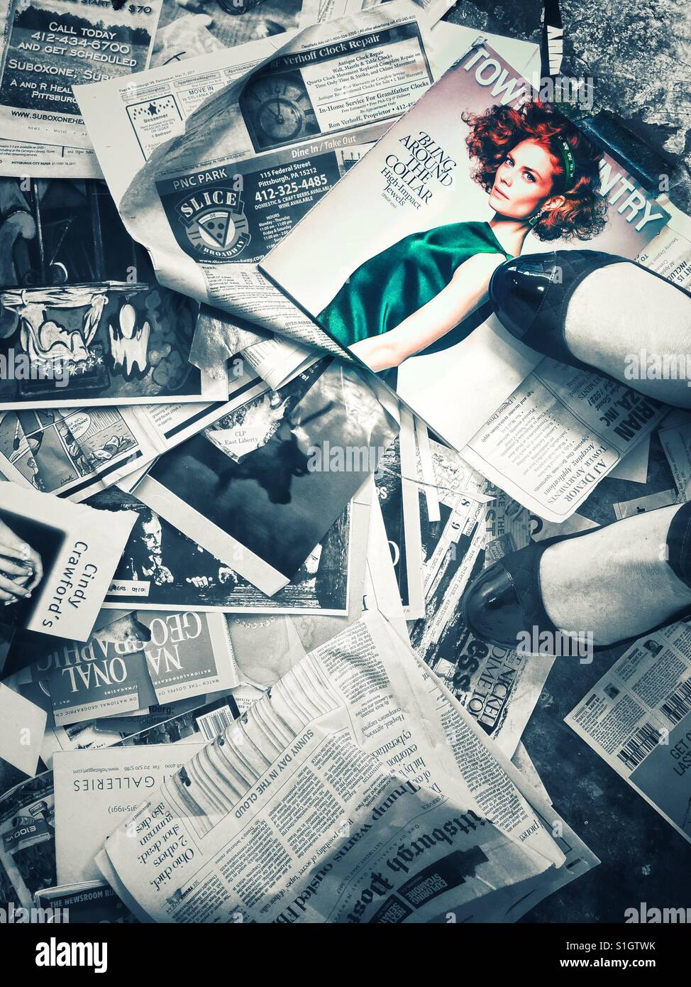 An abstract image of a woman standing on top of magazine clippings and newspapers strewn on the floor Stock Photo