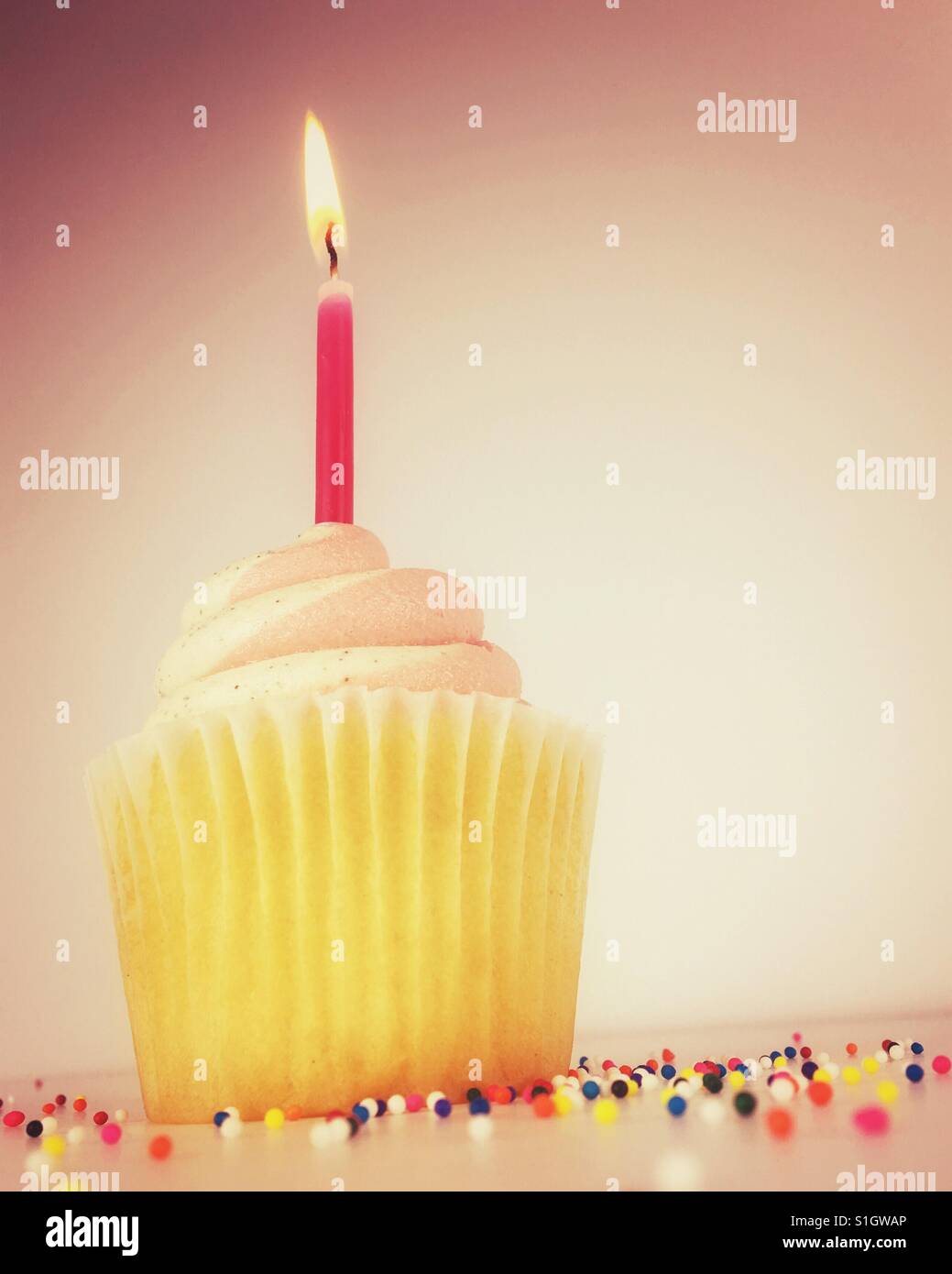 Frosted cupcake with a lit birthday candle. Room for copy. - Smartphone Captured Stock Image