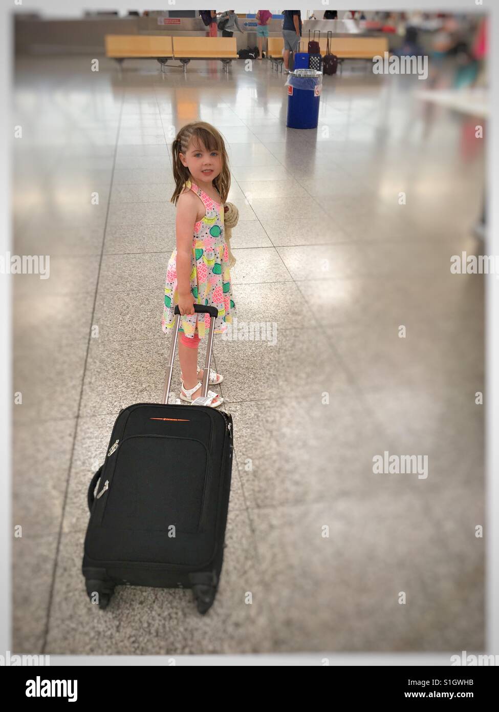 Girl with pull along suitcase at airport. Stock Photo