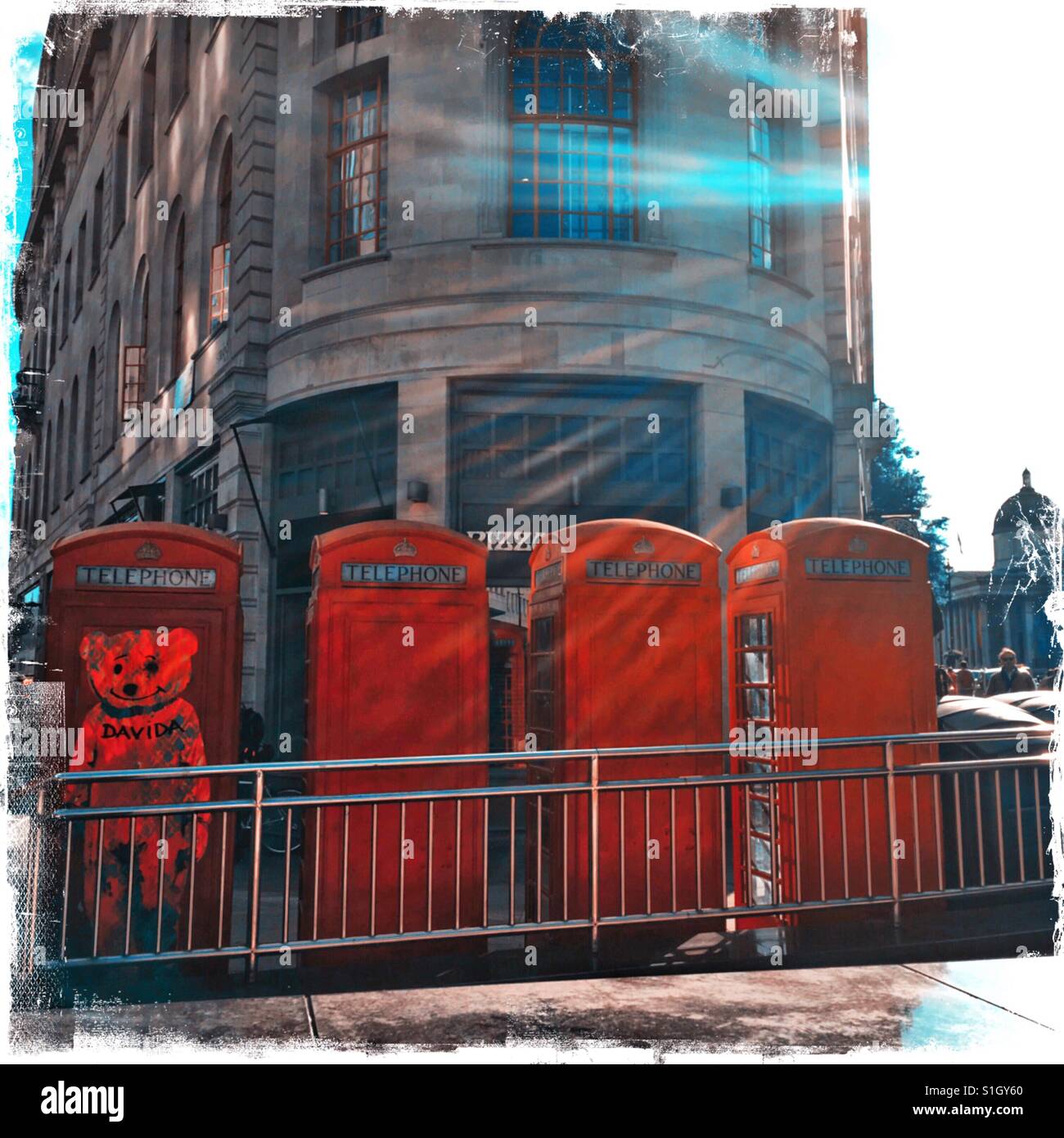 Red telephone boxes in London with a giant bear sticker / streetart Stock Photo