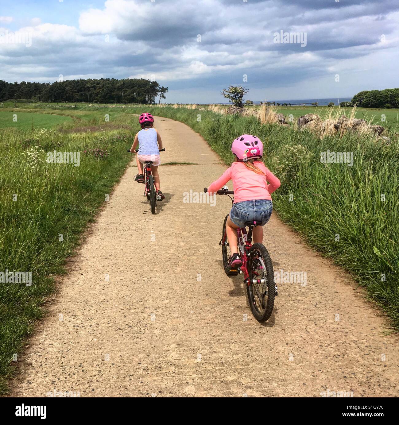 Two girls cycling on a country road. - Smartphone Captured Stock Image