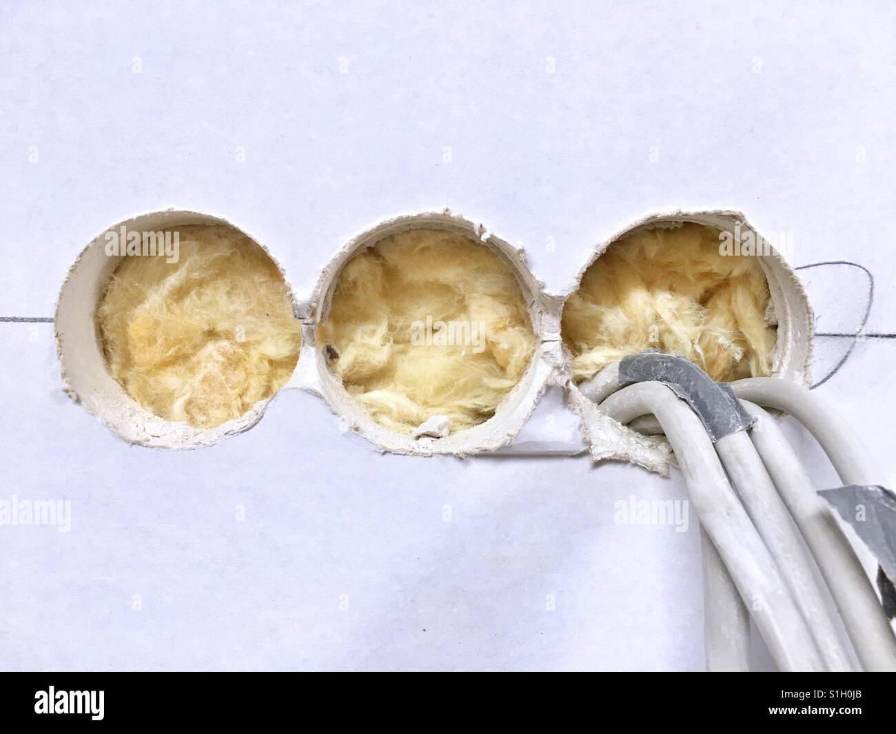 A drywall prepared for sockets with three drilled holes and cables hanging out Stock Photo