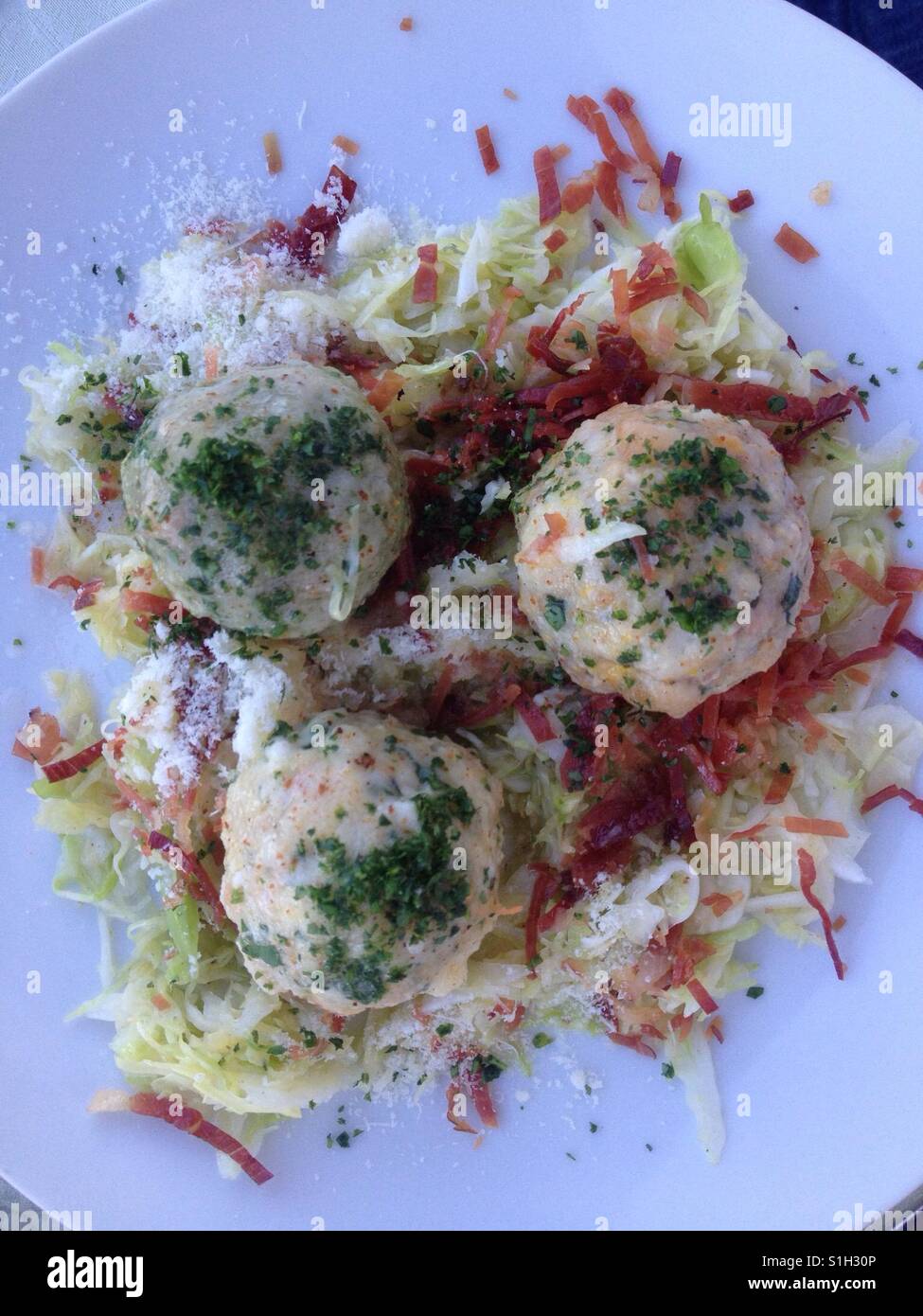 Three dumplings on a bed of mixed cabbage and ham, a traditional Alpine